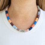 Colorful beaded necklace worn by a person on a plain background