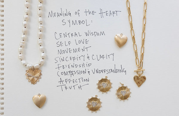 Picture of a fresh water pearl necklace and chain toggle necklace with several different gold heart and disc pendants.  Text reads, "Meaning of the Heart Symbol: Central wisdom, self love, movement, sincerity & clarity, friendship, compassion & understanding, affection, truth."