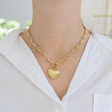 Picture of a gold chain link necklace with a gold toggle clasp and a large textured gold heart.