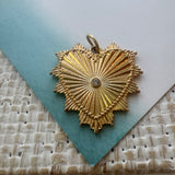Close up of a textured gold heart charm with a central diamond.
