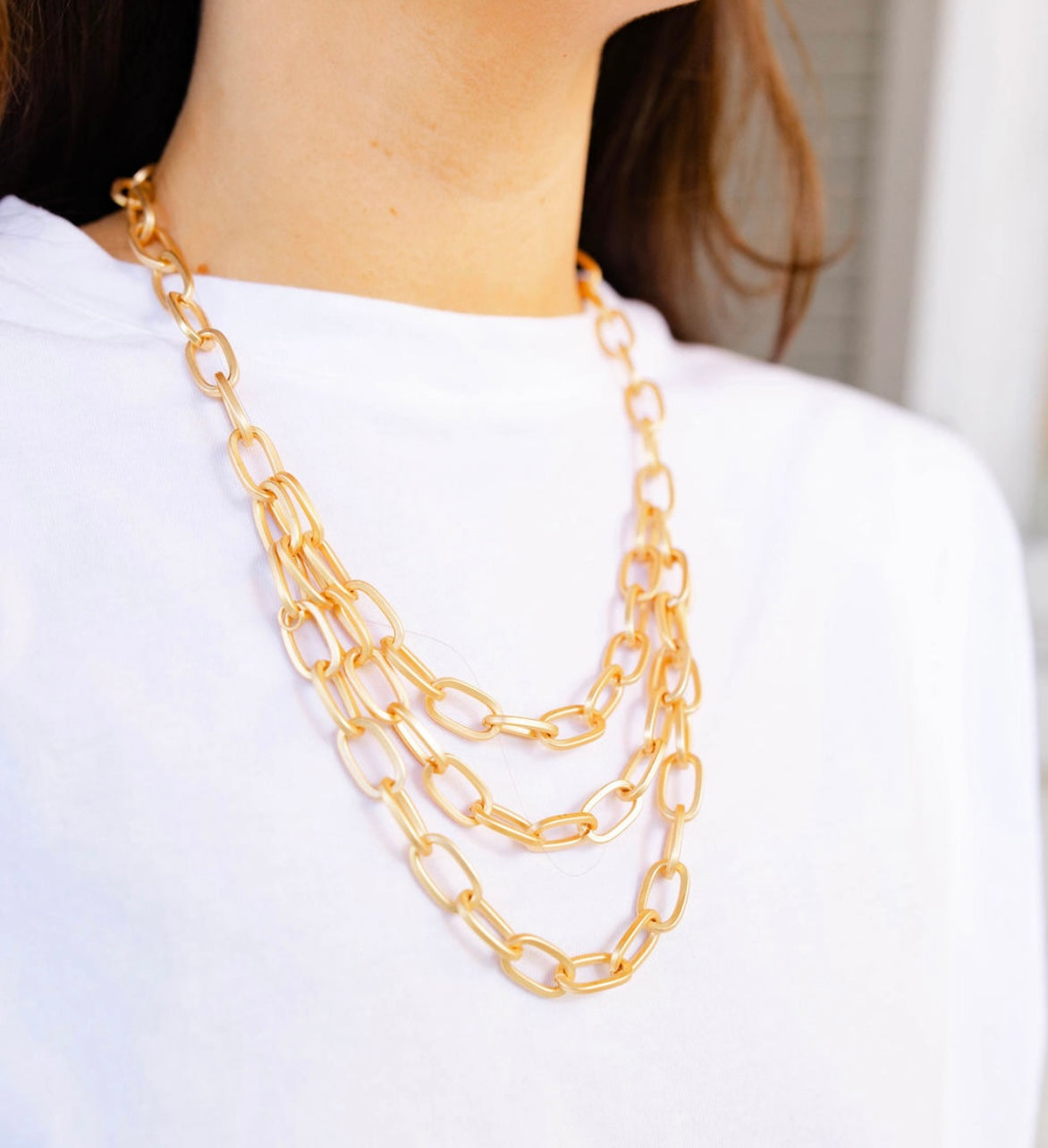 A girl wearing a multi layered gold chained necklace