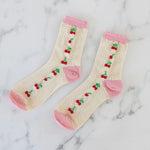 Pair of socks with cherry design and pink edging on a marble background