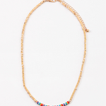 Dainty gold bead necklace with small red, yellow and turquoise beads at its center.