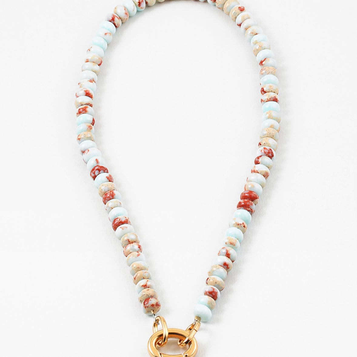 White bead necklace with rust colored flecks and a large gold carabiner clasp.