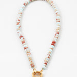 White bead necklace with rust colored flecks and a large gold carabiner clasp.