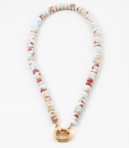 White bead necklace with rust colored flecks and a large gold carabiner clasp.