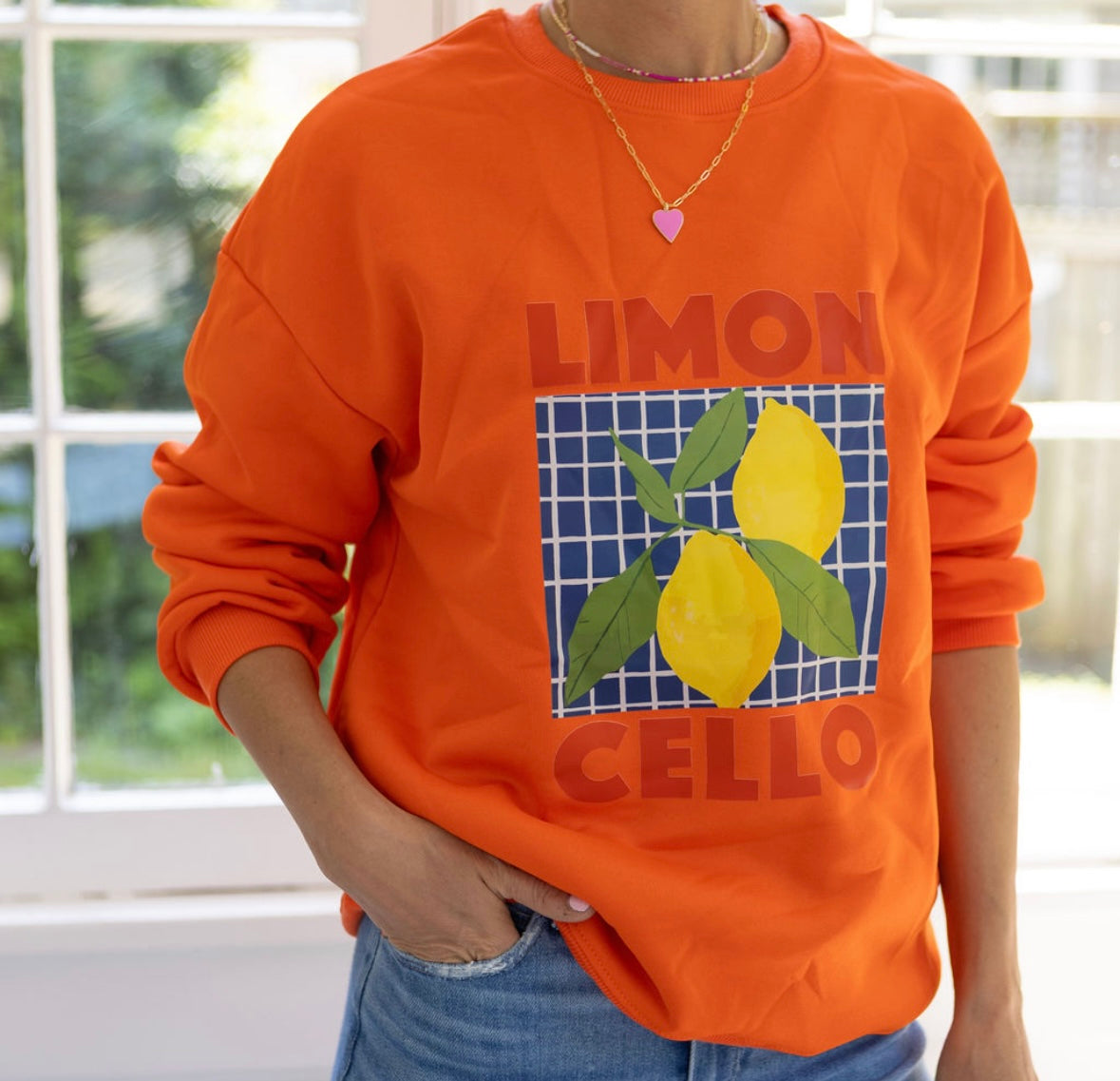 Person wearing an orange sweatshirt with lemon design and text