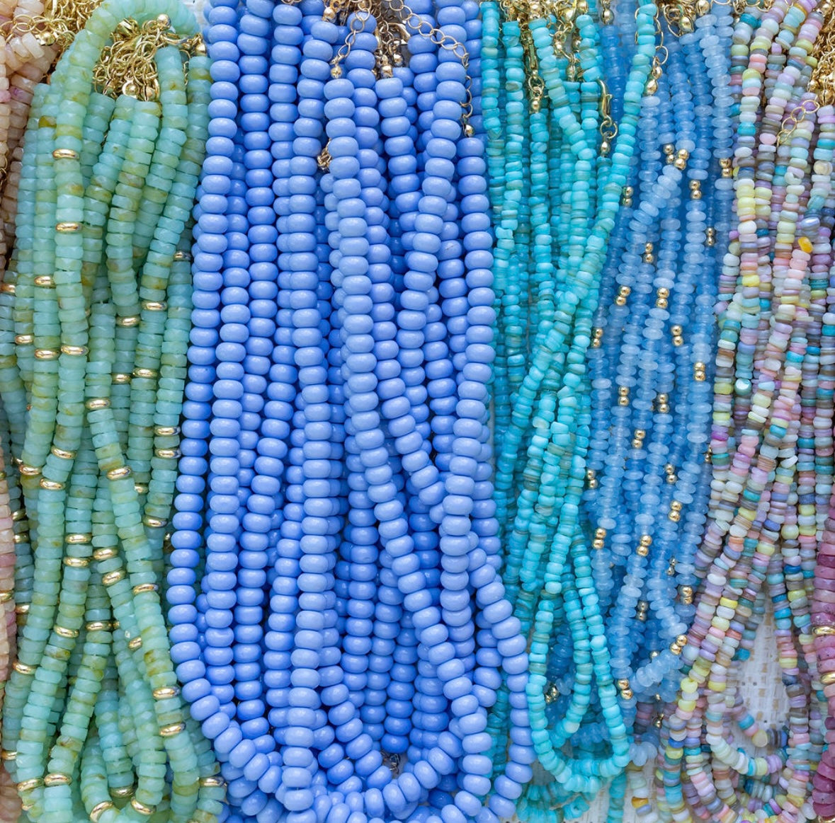 Close-up of colorful beaded necklaces with a focus on blue and green tones.