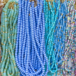 Close-up of colorful beaded necklaces with a focus on blue and green tones.