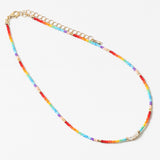 Multicolored rainbow beaded necklace with a gold chain on a white background