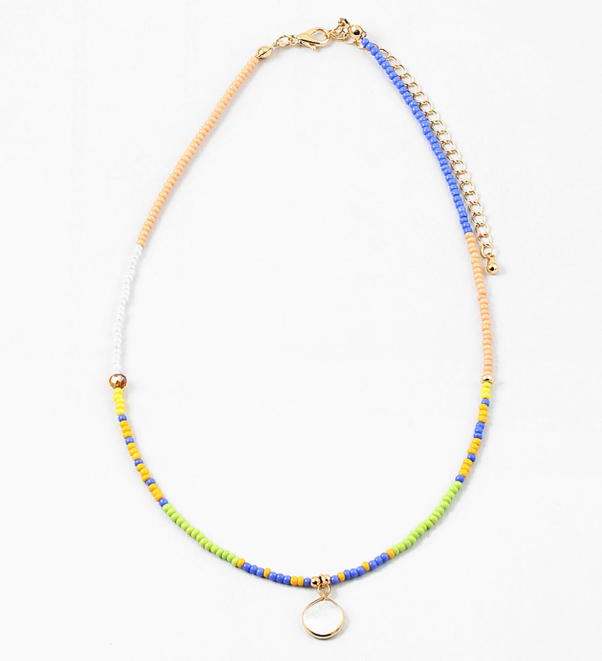 Dainty bead necklace in colors of blue, yellow, tan, green and white. Necklace has a small white disc pendant.