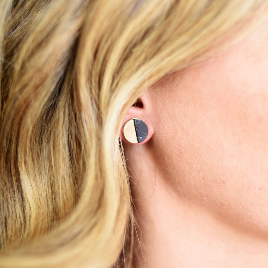 Picture of model wearing a disc stud that is half black and half cream colored.