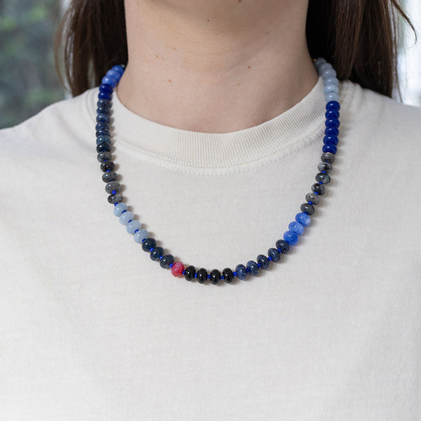 Model wearing a beaded necklace of varying shades of blue.