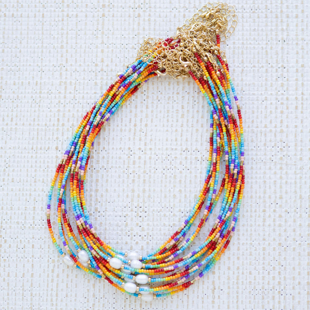 Multicolored beaded necklaces with gold clasps on a textured white background