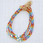 Multicolored beaded necklaces with gold clasps on a textured white background