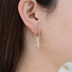 Picture of model wearing gold chain link earrings with the bottom link encrusted in pearls.