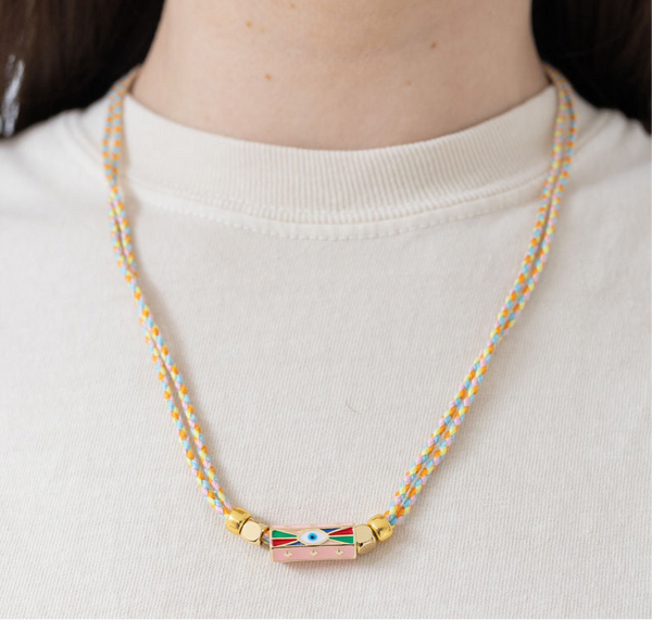 Picture of two braided strands that form a necklace with an evil eye pendant at its center.