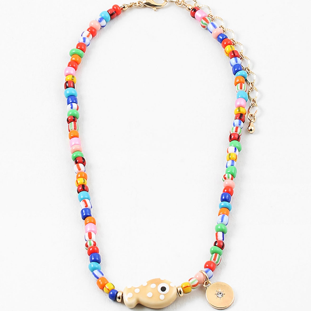 Picture of a bright multi-colored bead necklace with a tan fish bead and a gold disc pendant.