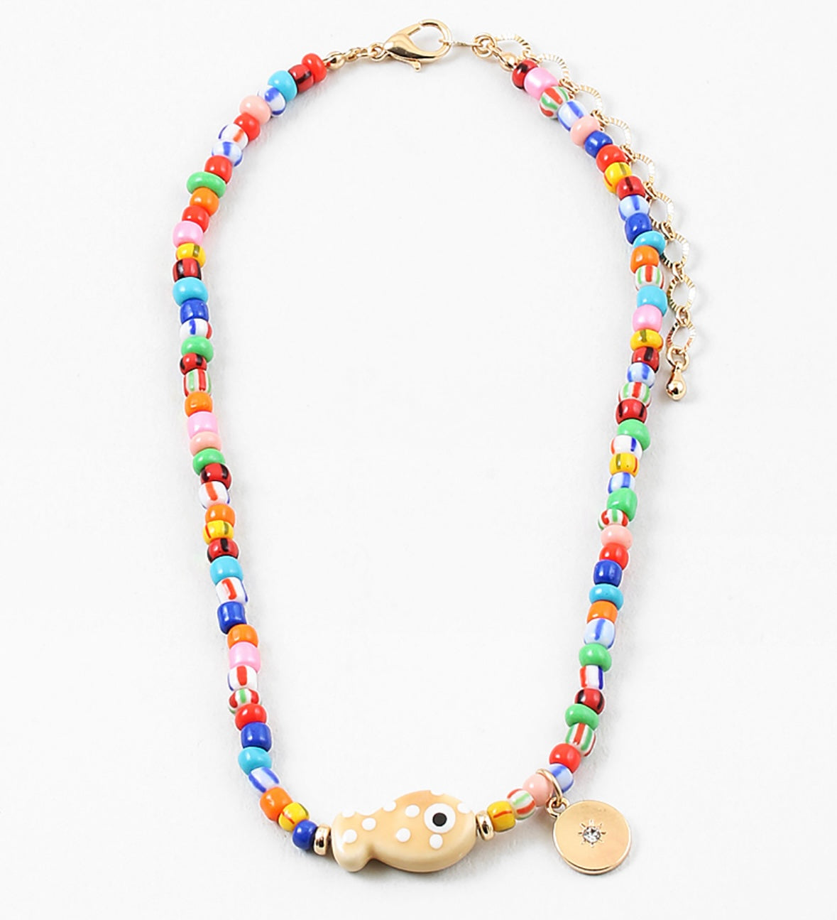 Picture of a bright multi-colored bead necklace with a tan fish bead and a gold disc pendant.