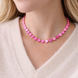 Person wearing a pink heart-shaped beaded necklace against a neutral background