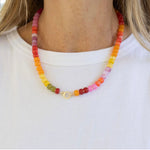 Colorful beaded necklace with a large gold clasp worn by a woman.