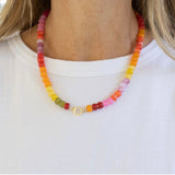 Colorful beaded necklace with a large gold clasp worn by a woman.