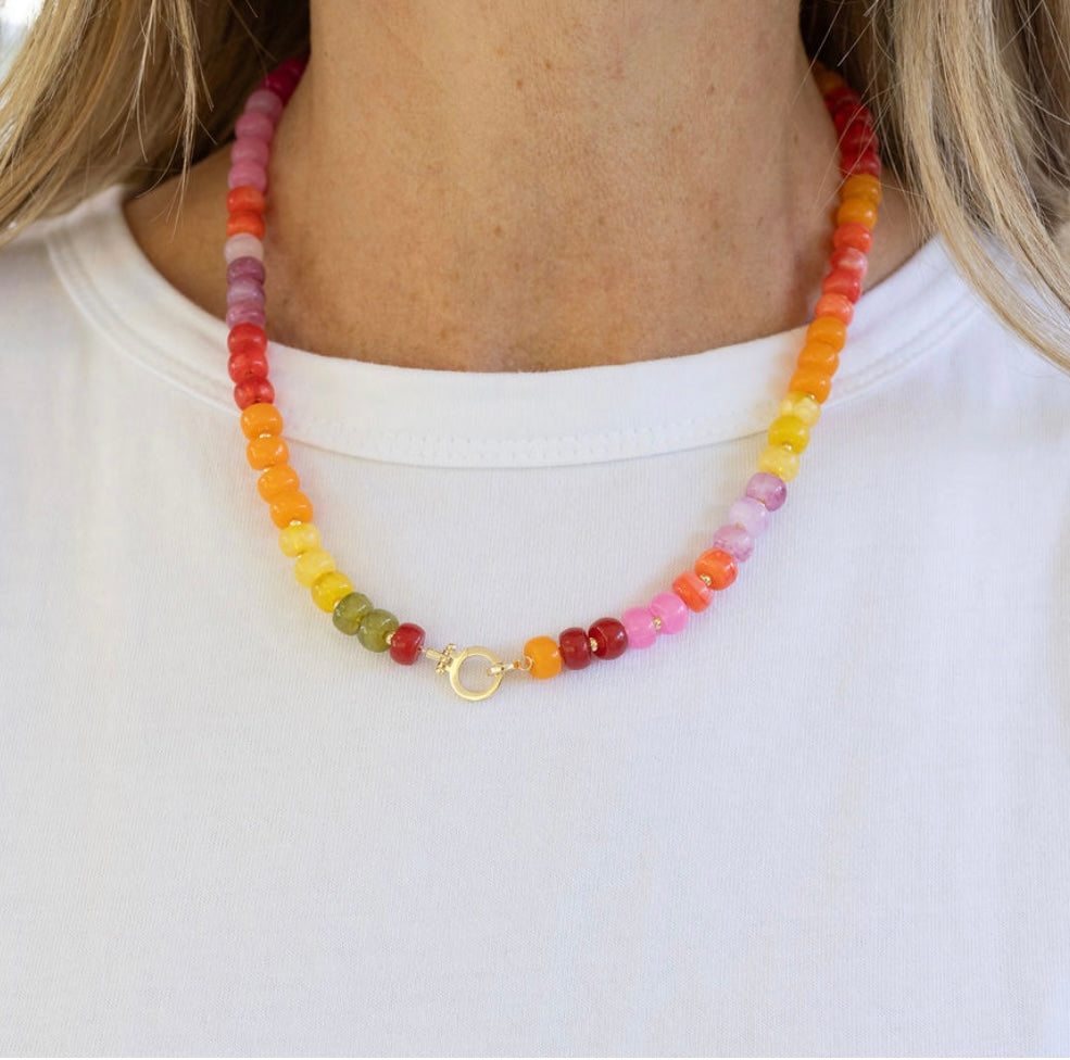 Colorful beaded necklace with a large gold clasp worn by a woman.