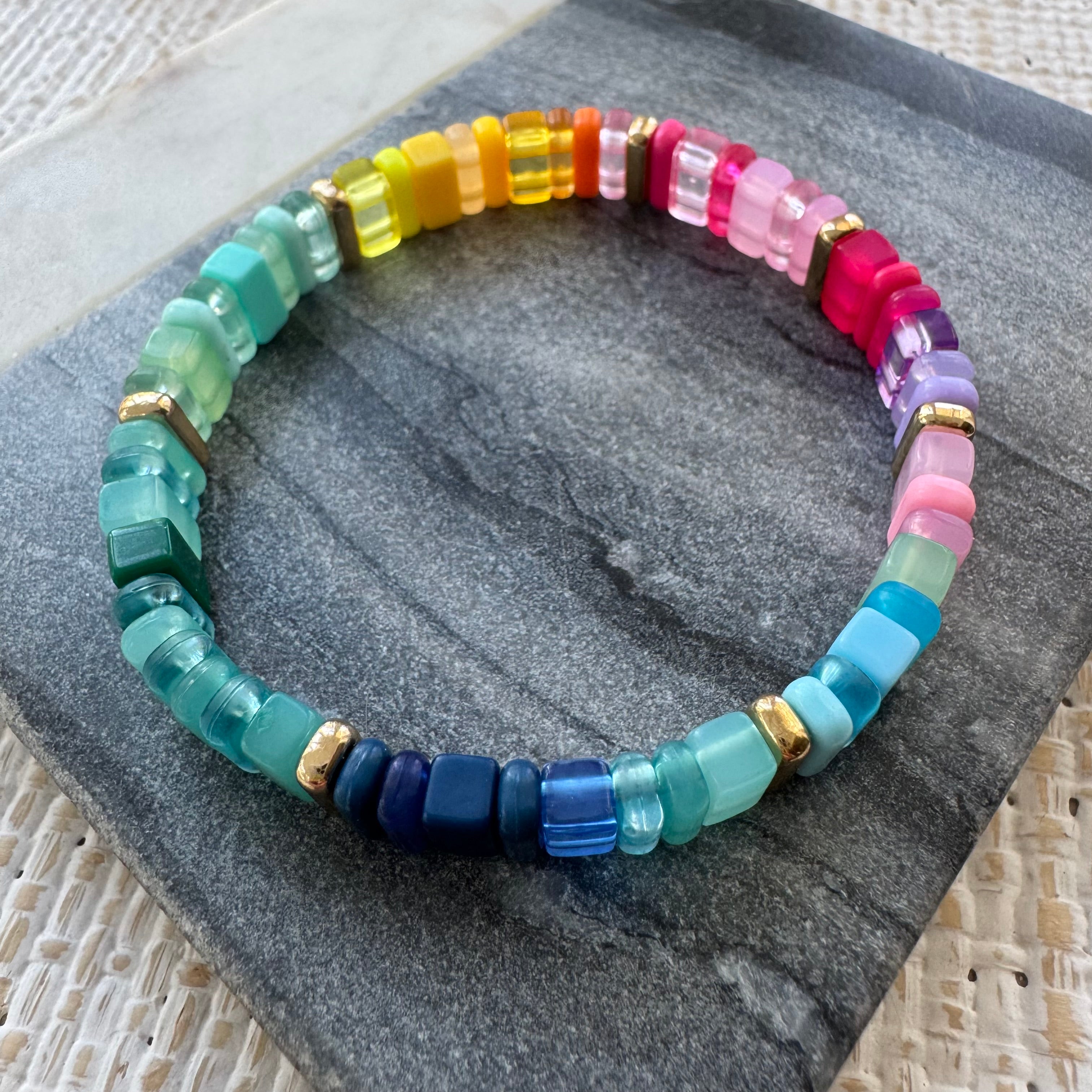 Picture of a multicolored rectangular beaded bracelet in clear and solid colors. Colors are greens, blues, pinks, purples and yellows.
