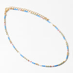 Delicate necklace with blue, white and gold beads and gold chain on a white background