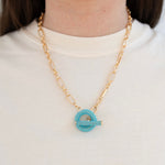 Model wearing a gold toggle chain with turquoise beaded toggle.