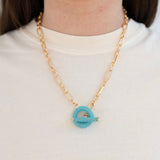 Model wearing a gold toggle chain with turquoise beaded toggle.