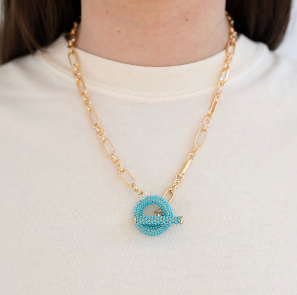 Model wearing a gold toggle chain with turquoise beaded toggle.