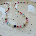 Colorful and clear beaded necklace on a speckled ceramic plate