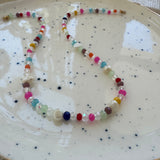 Colorful and clear beaded necklace on a speckled ceramic plate