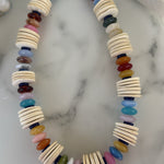 Colorful beaded necklace with thin natural wood disc beads on a marble surface