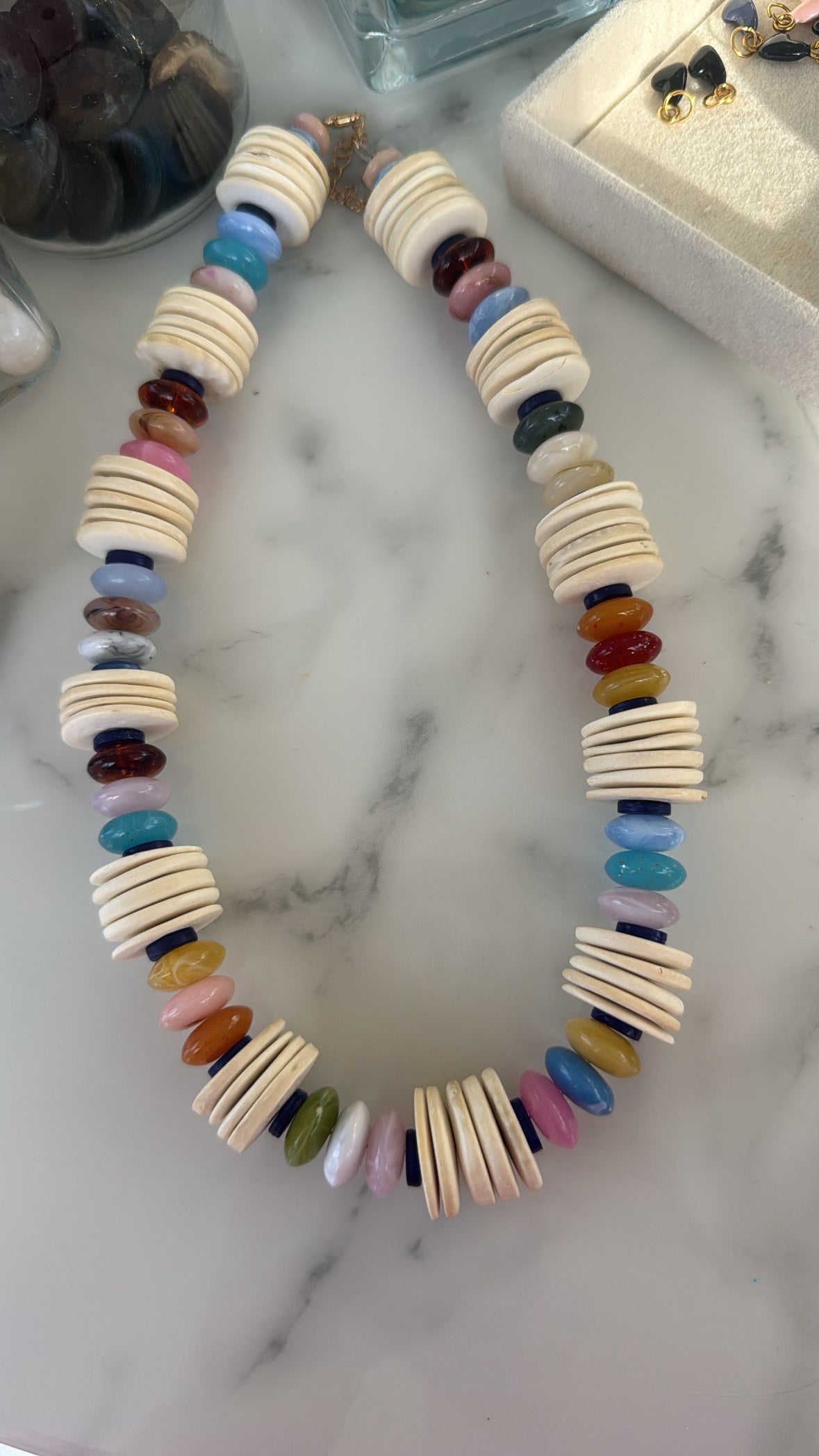 Colorful beaded necklace with thin natural wood disc beads on a marble surface