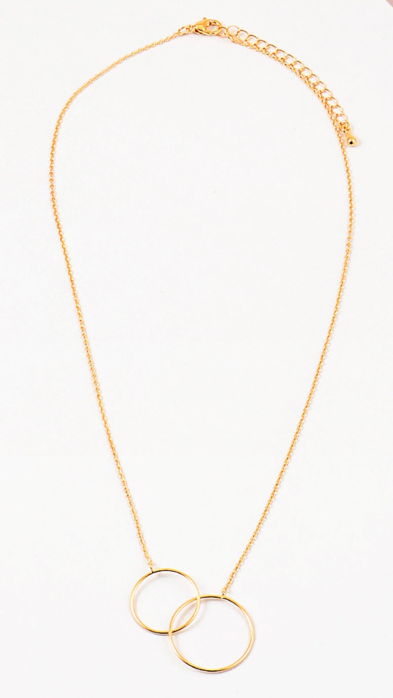 A gold-colored necklace with two interlocking circles as the central pendant on a white background.