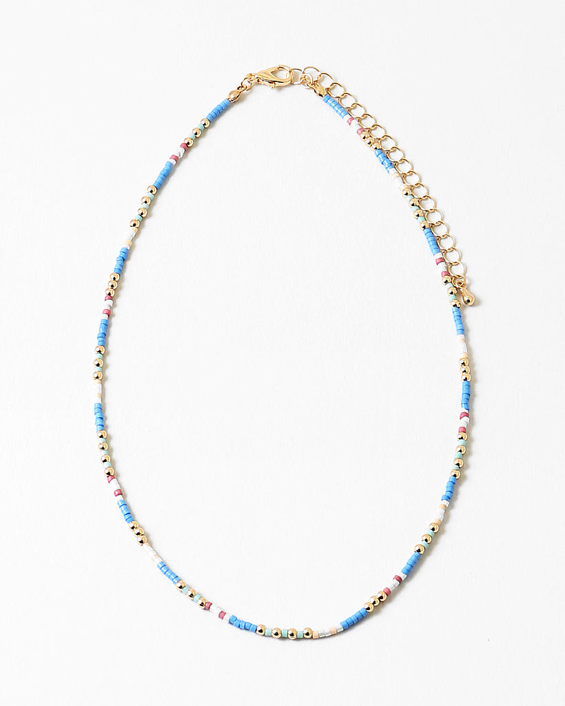Delicate necklace with blue, white and gold beads and gold chain on a white background