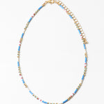 Delicate necklace with blue, white and gold beads and gold chain on a white background