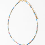 Delicate necklace with blue, white and gold beads and gold chain on a white background