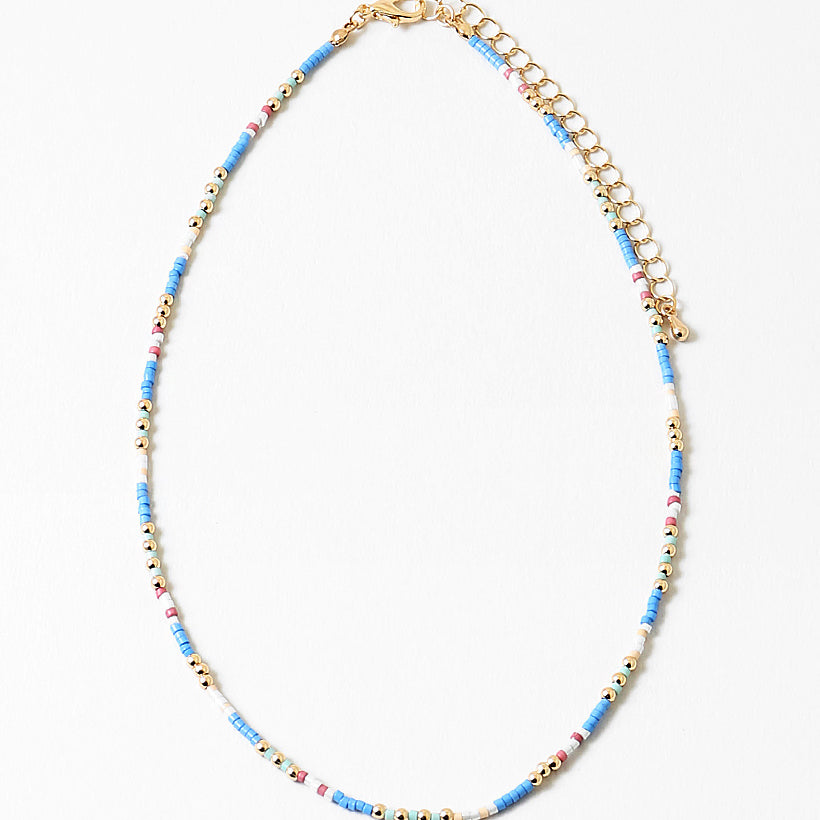 Delicate necklace with blue, white and gold beads and gold chain on a white background