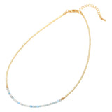Gold necklace with small blue and gray beads on a white background