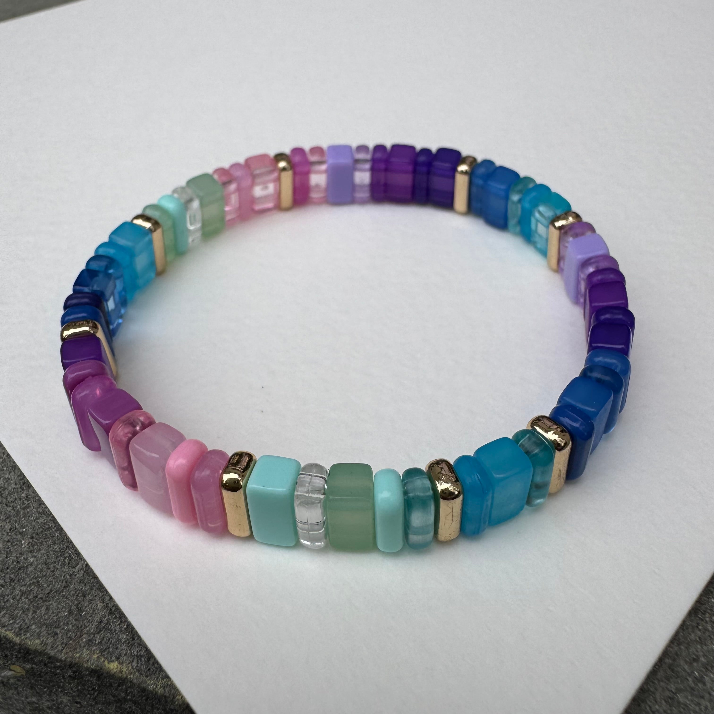 Picture of a multicolored bead bracelet in mostly shades of purples, pink, green and blues.