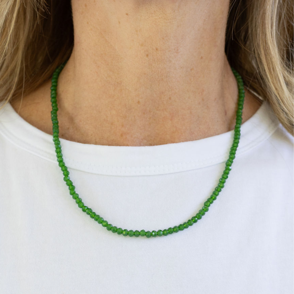 Green beaded necklace worn by a person on a white background