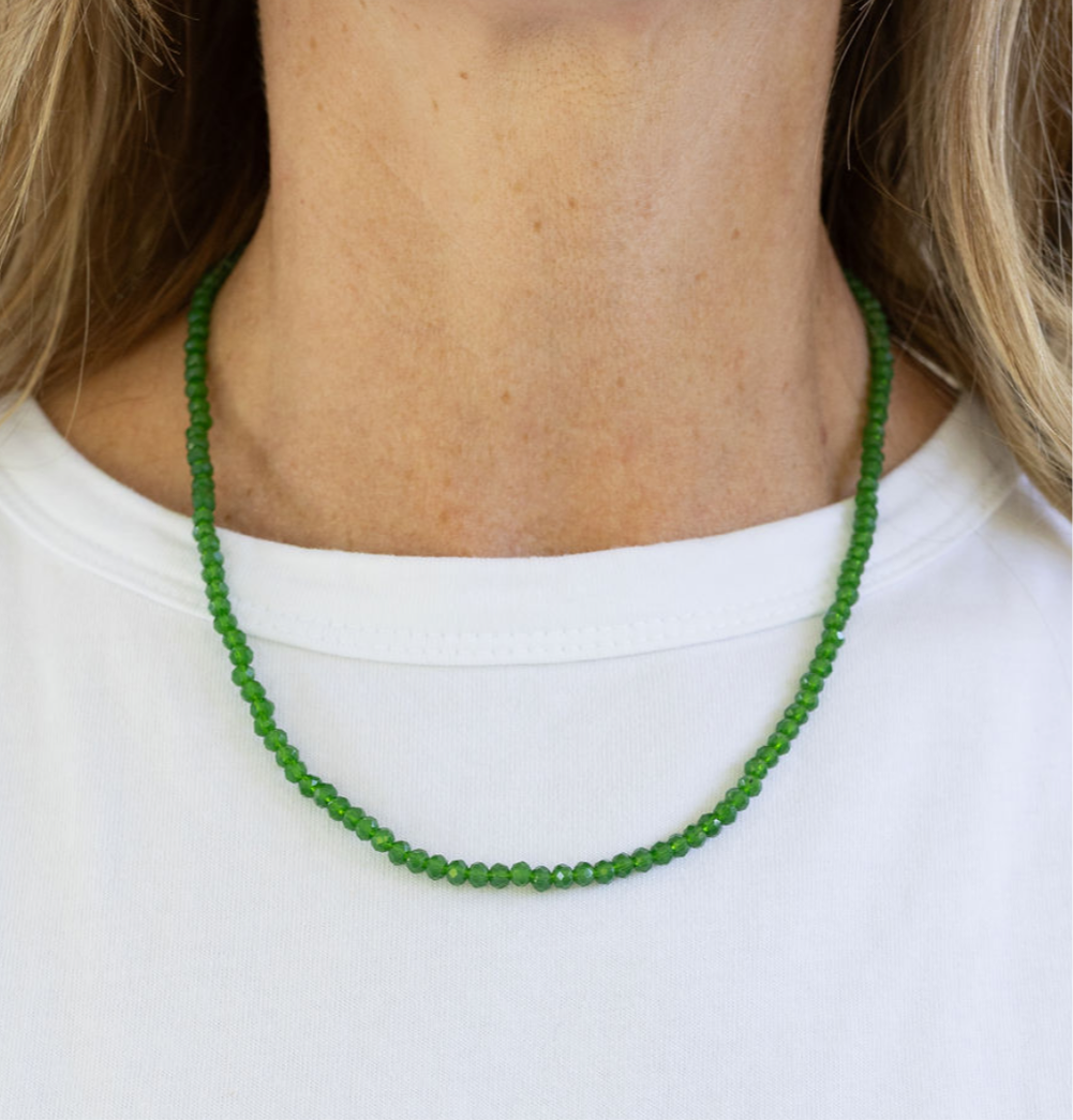 Green beaded necklace worn by a person on a white background