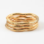 Set of three gold stretch bracelets on a white background