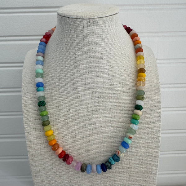 Picture of a jewelry display showing a beaded necklace. Beads are warm colors in yellow, green, reds and some blues