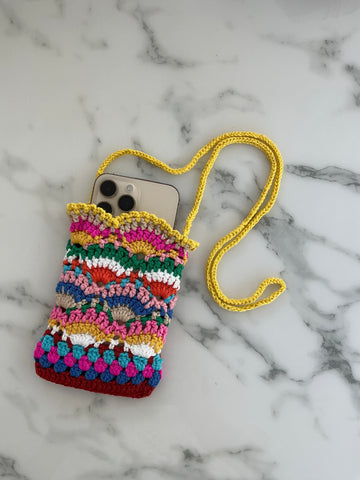 Picture of cell phone with a multi-colored crocheted cellphone bag with a yellow crocheted strap.