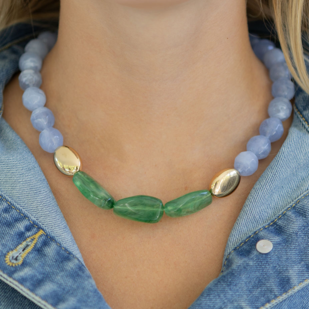 Necklace with blue and green beads worn by a person in a denim jacket