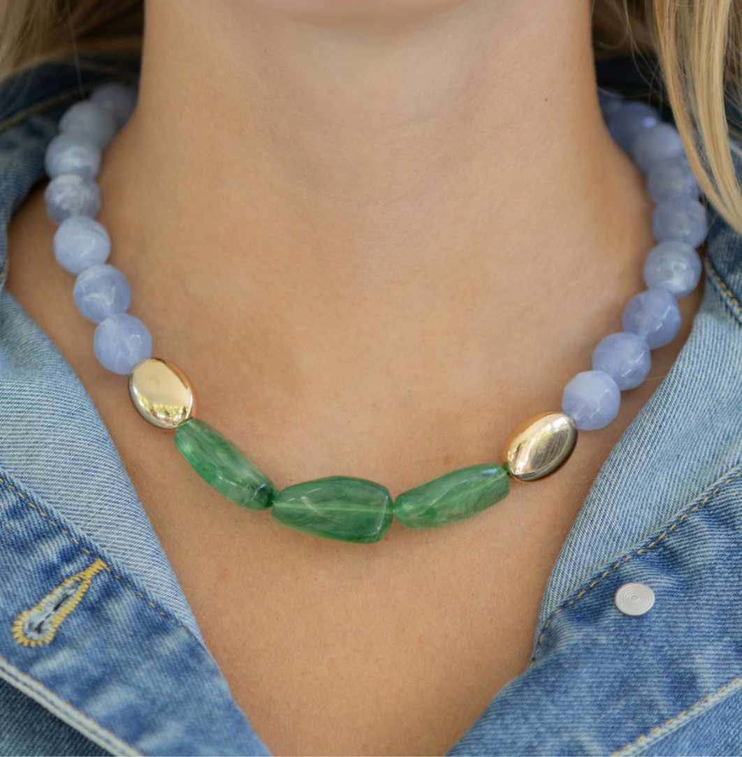 Necklace with blue and green beads worn by a person in a denim jacket